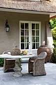 Stone table and wicker chairs on terrace adjoining country house