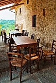 Dining tables and chairs next to stone wall on roofed terrace