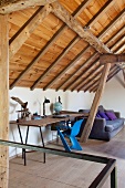 Schlichter Arbeitstisch und blau lackierter Schalenstuhl im Dachgeschoss mit Holzdecke