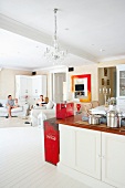 Offene Landhaus-Küche in modernem Wohnraum mit Gästen in der Loungeecke