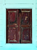 Geschlossene Fensterläden aus Holz in türkisfarbener Hausfassade