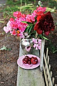 Bouquet in silver vase and plate of fruit on rustic wooden bench