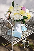 Bouquet of garden flowers in white case on white-painted wire mesh shelf