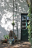 Wooden ladder and watering can in front of simple house with wooden door
