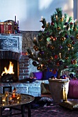 Christmas tree in ceramic pot in front of brick fireplace with Oriental tray table in foreground
