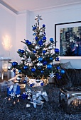 Christmas tree with blue and silver baubles on flokati-style rug in corner of living room