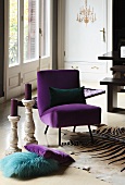 Chair with purple velvet upholstery on zebra-skin rug; scatter cushions and candlesticks on floor