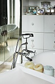 Free-standing bathtub with vintage tap fittings next to mirrored wall
