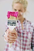 Renovating - woman holding paintbrush dipped in paint in hand