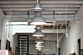 Row of pendant lamps with metal lampshades hanging from simple wooden ceiling in restaurant interior