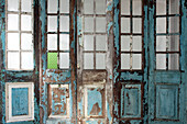 Abblätternde Farbe an Holzwand mit Sprossenfenstern und Türen