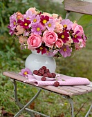 Pink summer bouquet and dish of raspberries on old folding chair in garden
