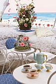 Coffee table with elegant coffee service; a flower arrangement with pink Gerberas behind it