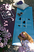 Girl plays with natural materials on yoga mats in the garden