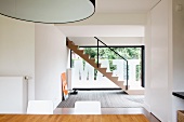 Blick über Essplatz in offenem Designer Wohnraum mit Treppe vor Glasfront beklebt mit Folienbuchstaben