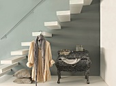 Modified Rococo chest of drawers below floating staircase and dress hanging from coathanger