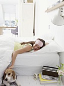 Smiling woman in bed caressing dog