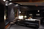 Minimalistischer Esstisch mit gepolsterten Bänken vor offener Küche im Wohnraum mit dunklen Farben