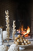 Bowl of artificial fruit and antique ornaments on table in front of open fire