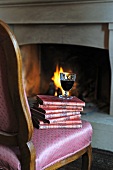 Glass of red wine on stack of books by the fireplace