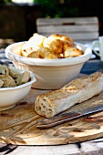 Baguette and bowl of croissants on wooden board