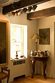 Krüge und Kannen auf antikem Beistelltisch in Zimmerecke neben Fenster