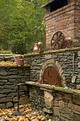 Corner of terrace with stone walls, oven and vintage copper watering can in Mediterranean garden