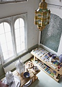 View down into ceramics workshop in industrial interior - various tile samples and Moroccan-style lanterns on wooden table