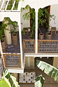 Potted trees on pergola balcony of Mediterranean house and view of courtyard below