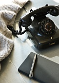 Black vintage telephone, notepad and pen