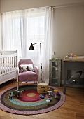 Retro standard lamp next to armchair and toys on round rug in simple child's bedroom