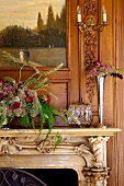 Vase of flowers and flower arrangement on carved mantelpiece against wooden wall with integrated painting