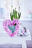 Small, heart-shaped wreaths of hyacinth florets in front of bowl of grape hyacinths