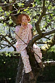 Little girl sitting in a tree eating an apple