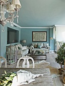 Blumenzweige auf Tisch und Loungeecke mit weisser Polstersofagarnitur vor hellblau getönten Wänden im Wohnzimmer