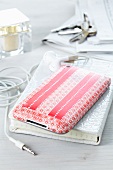 iPhone decorated with red-patterned tape, earphones, notebook with white mock croc cover