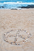 Peace symbol made of pebbles and shells on a sandy beach