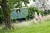 Two little blond girls running to a garden shed