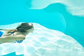 Frau im Bikini taucht im Swimmingpool