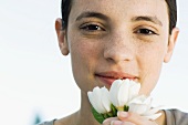 Young woman holding white flowers up to face