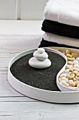 Yin and Yang dish with white pebbles on black lava sand contrasting with light pebbles
