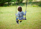Child playing on swing in garden