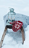 Woollen mitten and lantern in snow