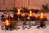 Christmas arrangement with candles, pine cones and coins