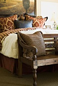 Rustikale Holzbank an Bettende eines Doppelbettes