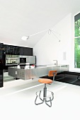 Retro Barhocker vor Küchentheke aus Edelstahl in minimalistischer Küche mit schwarzem Einbauschrank