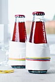 Drip catchers on drinks bottles; paper napkins held in place with rubber bands