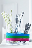 Glass containers used as cutlery holders and decorated with rubber bands