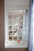 Blick durch Sprossenfenster einer Loggia in Loungeecke mit Sessel
