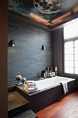 Modern bathroom - bathtub against wall with dark slate tiles and astronomical painting on ceiling